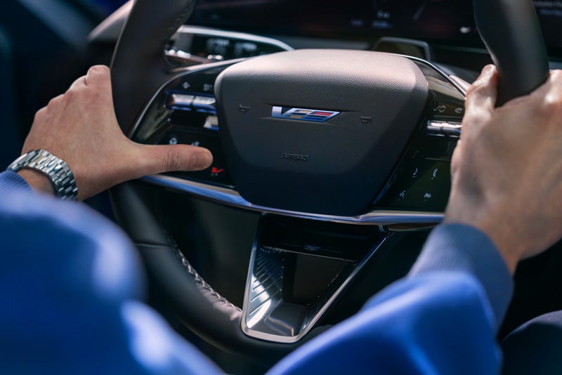Close-up of a Man About to Press the V-Button on the 2026 OPTIQ-V Steering Wheel | Navarre Cadillac in Lake Charles LA