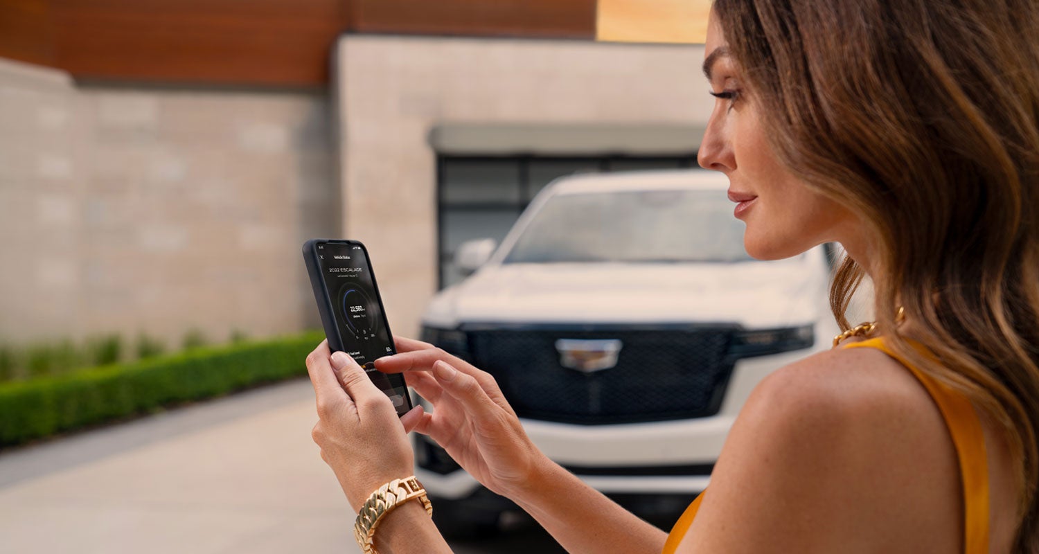 lady checking her mobile with a Cadillac vehicle background | Navarre Cadillac in Lake Charles LA